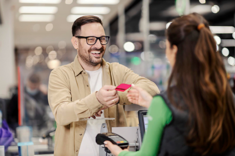 happy-man-giving-credit-card-cashier-supermarket-paying-check