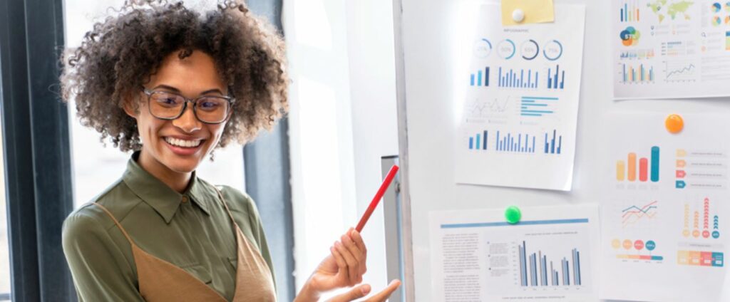 Mulher sorrindo explicando graficos em quadro branco